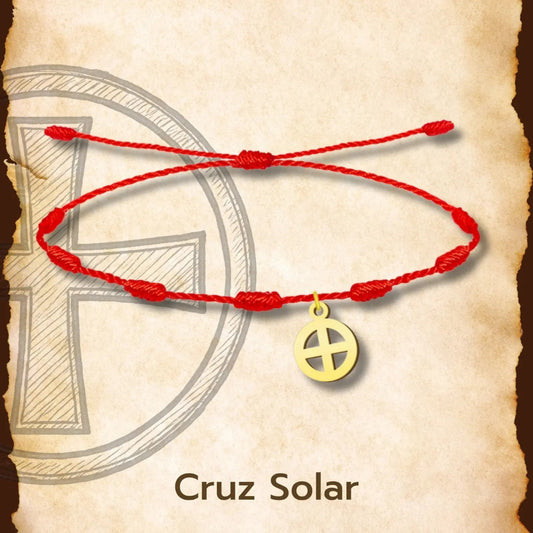 Pulsera de hilo rojo con 7 nudos y dije de Cruz Solar en acero dorado sobre fondo de pergamino.