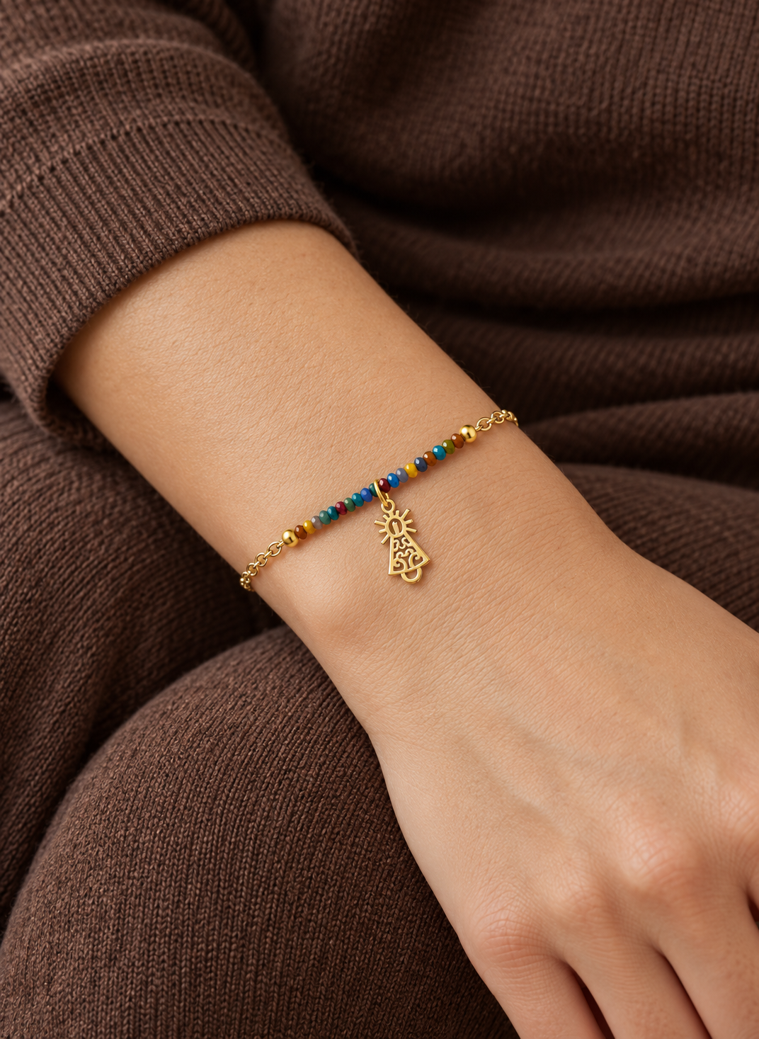 Pulsera multicolor Virgen del Pilar en una muñeca con jersey marrón