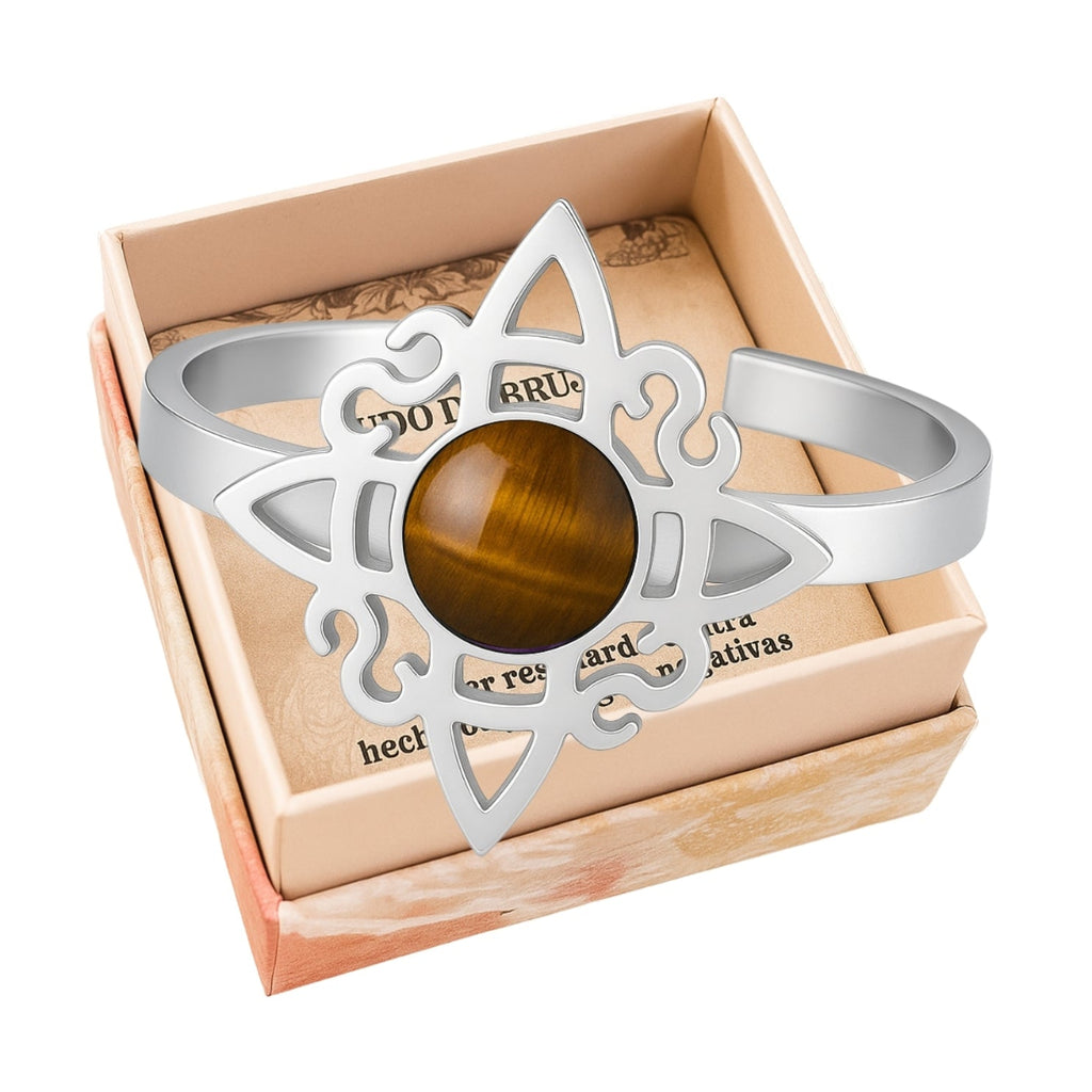 Anillo abierto de acero plateado con diseño de Nudo de Bruja y piedra central de Ojo de Tigre marrón con destellos dorados.