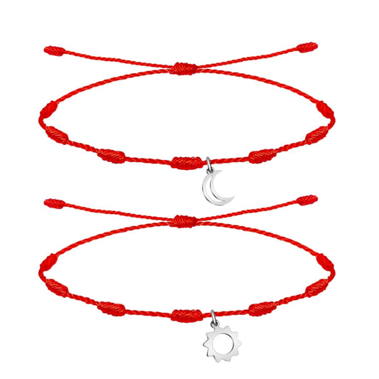 Pack de dos pulseras de hilo rojo de 7 nudos con charms de Sol y Luna en acero inoxidable plateado, diseño minimalista para parejas que simboliza la conexión entre el día y la noche.