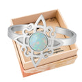 Anillo abierto de acero plateado con diseño de Nudo de Bruja y piedra central de Opalina con reflejos iridiscentes.