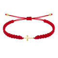 Pulsera de hilo rojo trenzado con cruz latina horizontal en acero dorado y nudo ajustable.