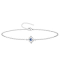 Pulsera de cadena fina en acero inoxidable plateado con charm del Nudo de Bruja y detalle central de Ojo Turco azul, amuleto de protección elegante.