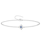 Pulsera de cadena fina en acero inoxidable plateado con charm del Nudo de Bruja y detalle central de Ojo Turco azul, amuleto de protección elegante.