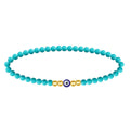 Pulsera de cuentas turquesas con ojo turco central azul y detalles en bolas doradas de acero.