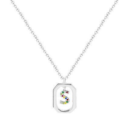 Collar plateado con inicial S en marco geométrico, cristales multicolor. Acero inoxidable 100%. Tarjeta con mensaje "Con S comienzan los Sueños".
