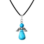 Colgante con forma de ángel hecho con cuentas de piedra turquesa y alas de metal plateado, montado sobre cordón negro.