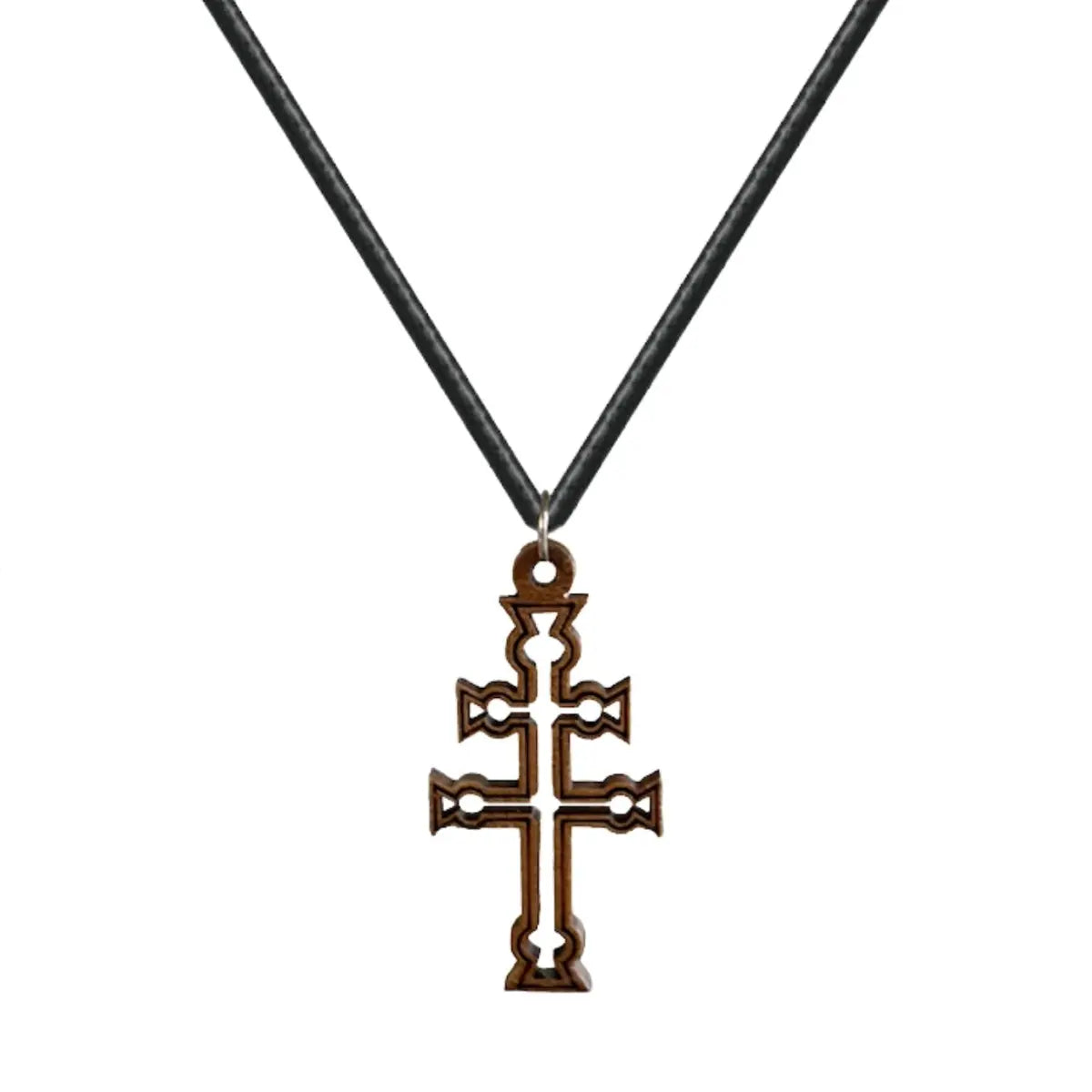 Colgante de la Cruz de Caravaca tallada en madera natural oscura con detalles calados y anilla de acero sobre fondo blanco