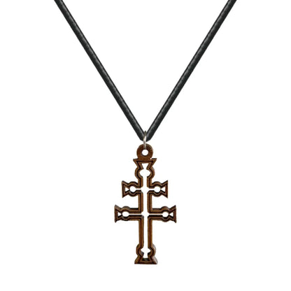 Colgante de la Cruz de Caravaca tallada en madera natural oscura con detalles calados y anilla de acero sobre fondo blanco