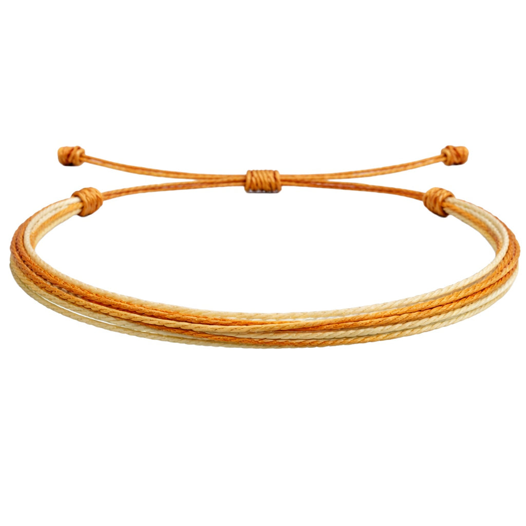 Vista completa de pulsera multihilo naranja y beige con cordones paralelos y extremos anudados