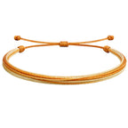 Vista completa de pulsera multihilo naranja y beige con cordones paralelos y extremos anudados