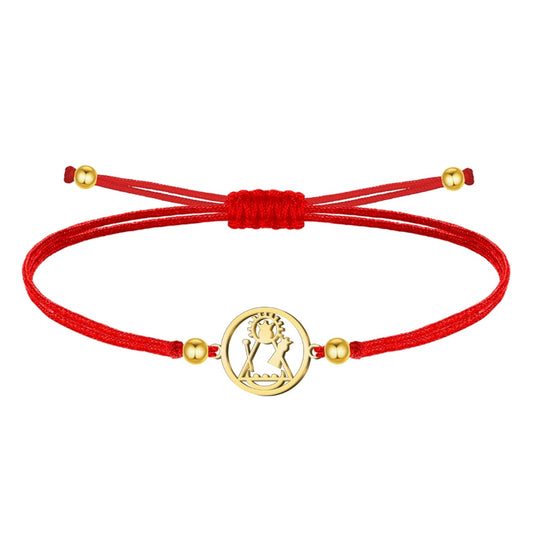 Pulsera de hilo encerado rojo ajustable con medalla central circular de acero inoxidable dorado, mostrando la silueta calada de la Virgen de Candelaria. Detalles de bolitas doradas en los extremos.