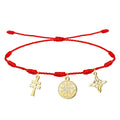 Pulsera de hilo rojo 7 nudos con tres amuletos de acero inoxidable dorado: Cruz de Caravaca (cruz de doble barra), Medallón del Tetragrammatón (centro) y Nudo de Bruja (derecha).