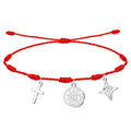 Pulsera de hilo rojo ajustable de 7 nudos con tres dijes de acero plateado: Cruz Latina minimalista (izquierda), Medallón del Tetragrammatón (centro) y Nudo de Bruja (derecha).