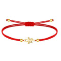 Pulsera de hilo rojo con un diseño central de la Cruz Egipcia (Ankh) que integra el símbolo del Ojo de Horus, fabricada en acero inoxidable con acabado dorado, decorada con esferas metálicas doradas y cierre ajustable de nudo corredizo.