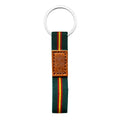 Llavero de cinta textil color verde Guardia Civil con bandera de España y parche de cuero marrón grabado con la Virgen del Pilar. Anilla plateada plana.