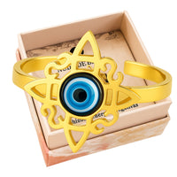 Anillo abierto de acero inoxidable dorado con diseño de Nudo de Bruja y amuleto central de Ojo Turco azul.