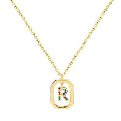 Collar con inicial R y marco geométrico, cristales multicolor y baño de oro 14K. Tarjeta con mensaje "Con R comienza el Resplandor". Stainless Steel.