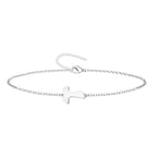 Pulsera de cadena fina con cruz Tau central en acero inoxidable de color plateado y cierre ajustable.
