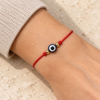 Pulsera roja con Ojo Turco azul y blanco en la muñeca. Escena ilustrativa generada con IA.