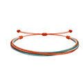 El naranja del cierre continúa entre cordones turquesa y líneas claras de una pulsera multihilo