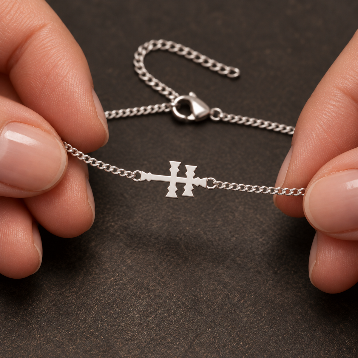 Pulsera plateada con Cruz de Caravaca sostenida entre los dedos. Escena ilustrativa generada con IA.