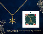 Collar dorado de copo de nieve junto a su tarjeta de regalo, sobre fondo oscuro.