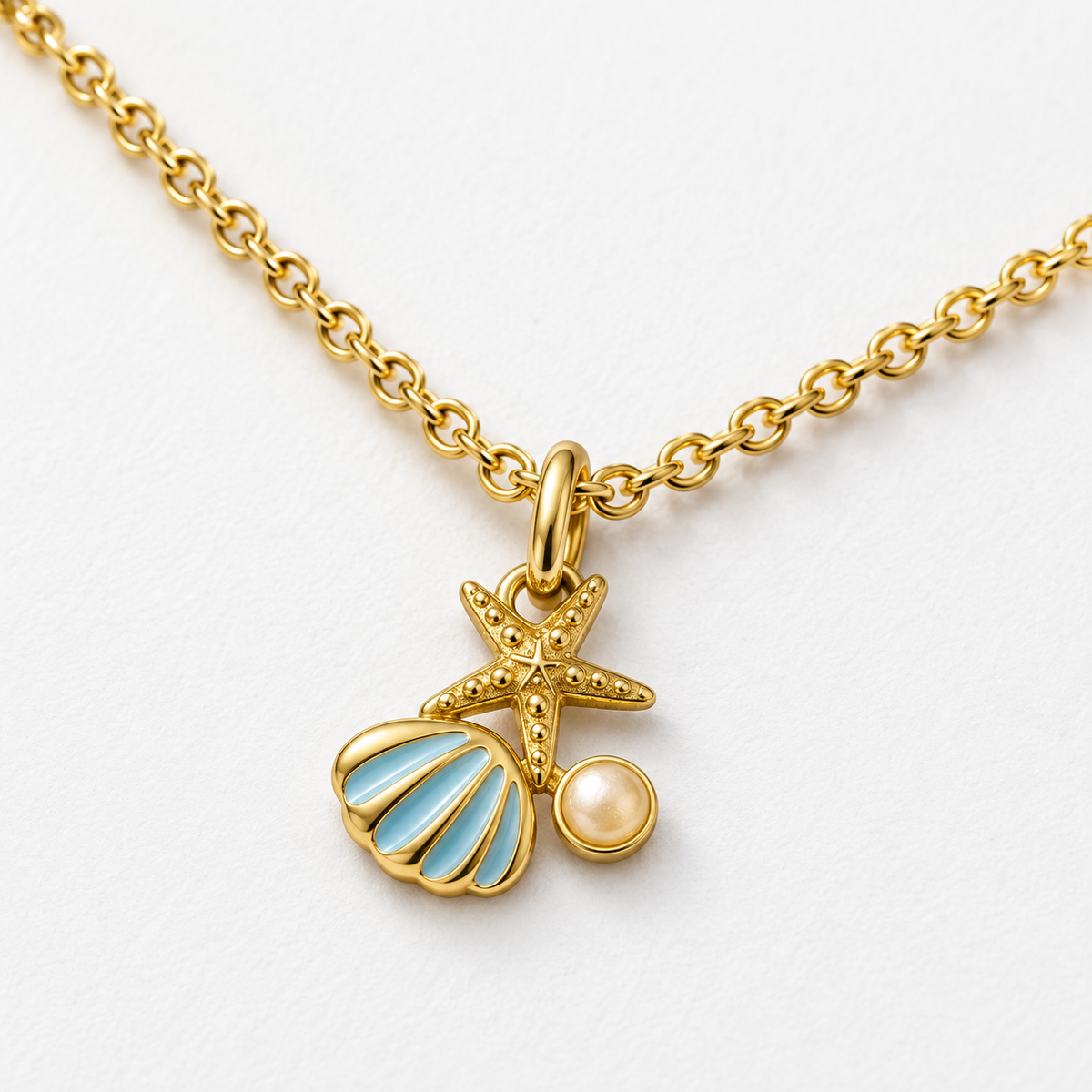 Collar dorado de concha y estrella de mar, detalle sobre una superficie blanca.