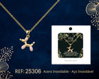 Balloon dog necklace in pink and gold tones beside its gift message card, on a dark background.