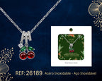 Collar de cerezas rojas junto a su tarjeta de regalo, sobre fondo oscuro.