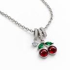 Collar de cerezas rojas, detalle sobre una superficie blanca.