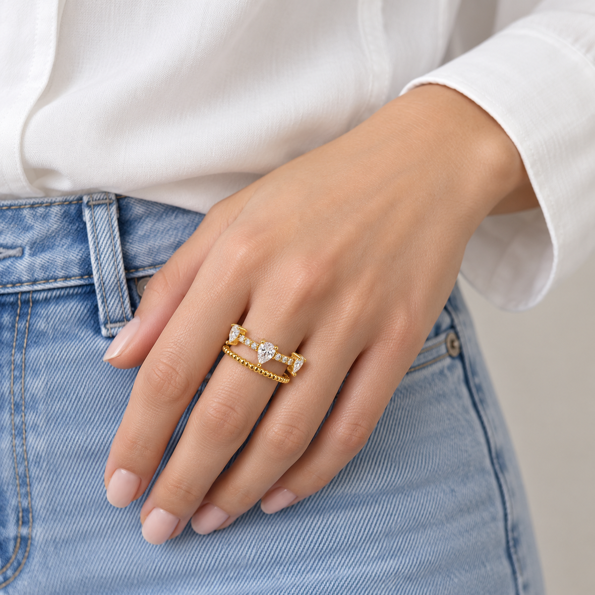 Anillo ajustable dorado de gotas y doble banda — combinación con ropa; imagen ilustrativa generada con IA, escala no verificada.