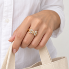 Anillo ajustable dorado de mariposa transparente — gesto cotidiano; imagen ilustrativa generada con IA, escala no verificada.