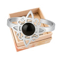 Anillo abierto de acero plateado con diseño de Nudo de Bruja y piedra central de Ágata Negra redonda.