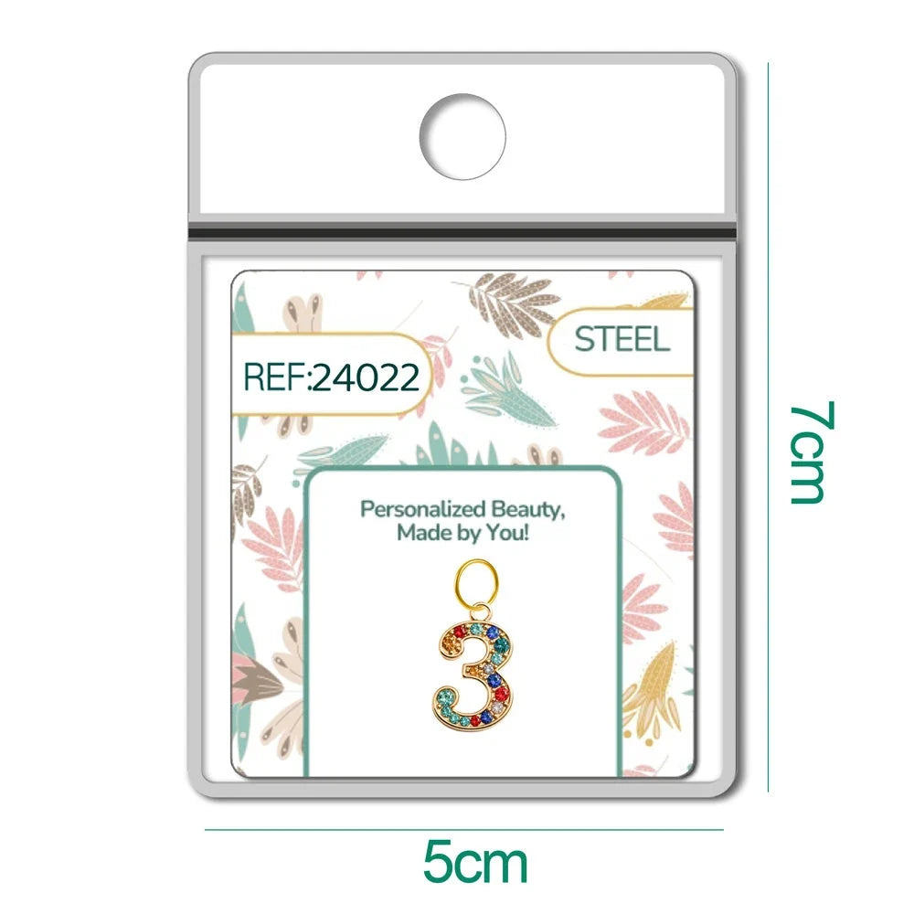 Charm dorado de número 3 con circonitas de colores con aro de acero, en blíster