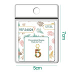 Charm dorado de número 5 con circonitas de colores con aro de acero, en blíster