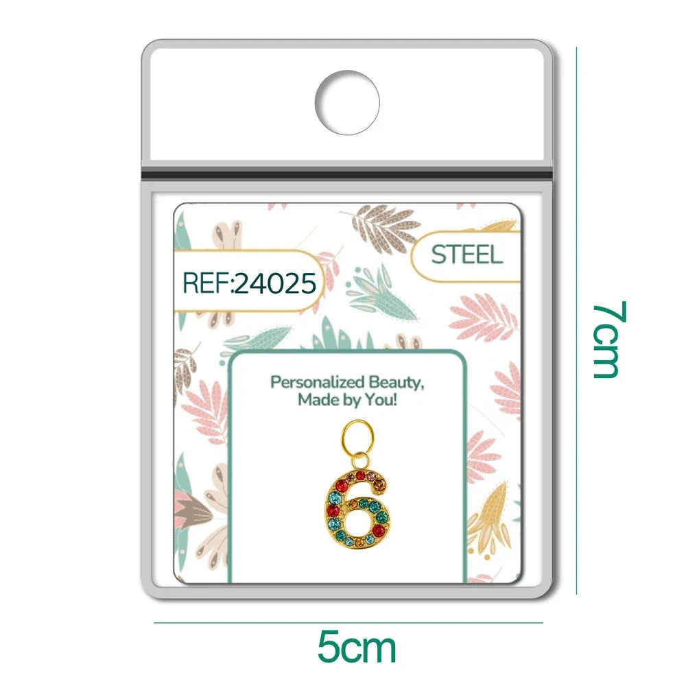 Charm dorado de número 6 con circonitas de colores con aro de acero, en blíster