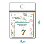 Charm dorado de número 7 con circonitas de colores con aro de acero, en blíster