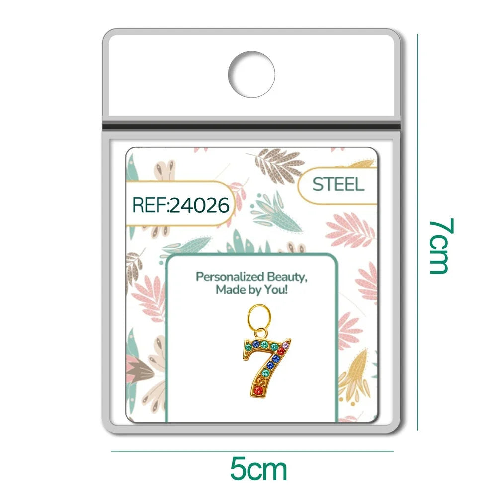 Charm dorado de número 7 con circonitas de colores con aro de acero, en blíster