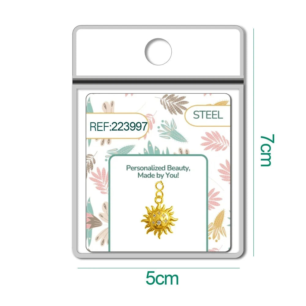 Charm dorado de sol con cara y seis circonitas con cierre de acero, en blíster