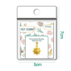 Charm dorado de sol con cara y seis circonitas con bola de acero con goma, en blíster