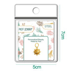 Charm dorado de sol con cara y seis circonitas con aro de acero, en blíster