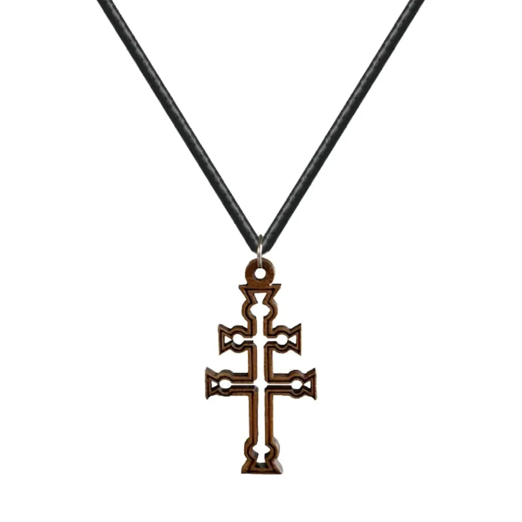 Colgante de la Cruz de Caravaca tallada en madera natural oscura con detalles calados y anilla de acero sobre fondo blanco