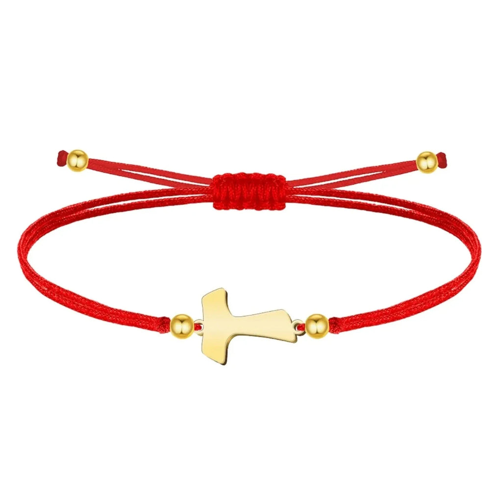 Pulsera de hilo rojo liso con cruz Tau central en acero dorado, esferas decorativas doradas y cierre ajustable.