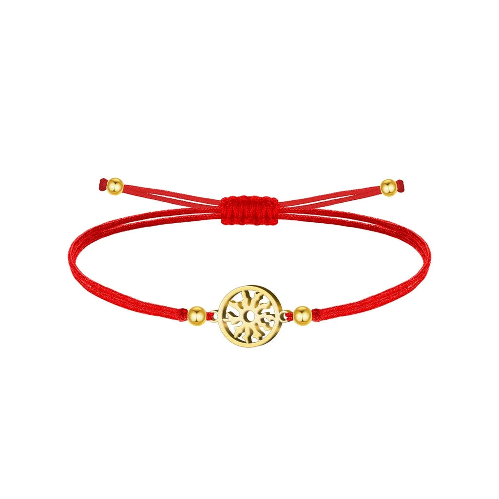 Pulsera de cordón rojo con cierre corredizo, motivo circular calado de Eguzkilore y cuatro cuentas de color dorado sobre fondo blanco