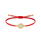 Pulsera de cordón rojo con cierre corredizo, motivo circular calado de Eguzkilore y cuatro cuentas de color dorado sobre fondo blanco