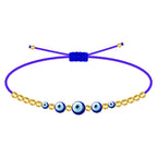 Pulsera de hilo azul ajustable con cinco amuletos de ojo turco de diferentes tamaños y cuentas doradas de acero inoxidable.
